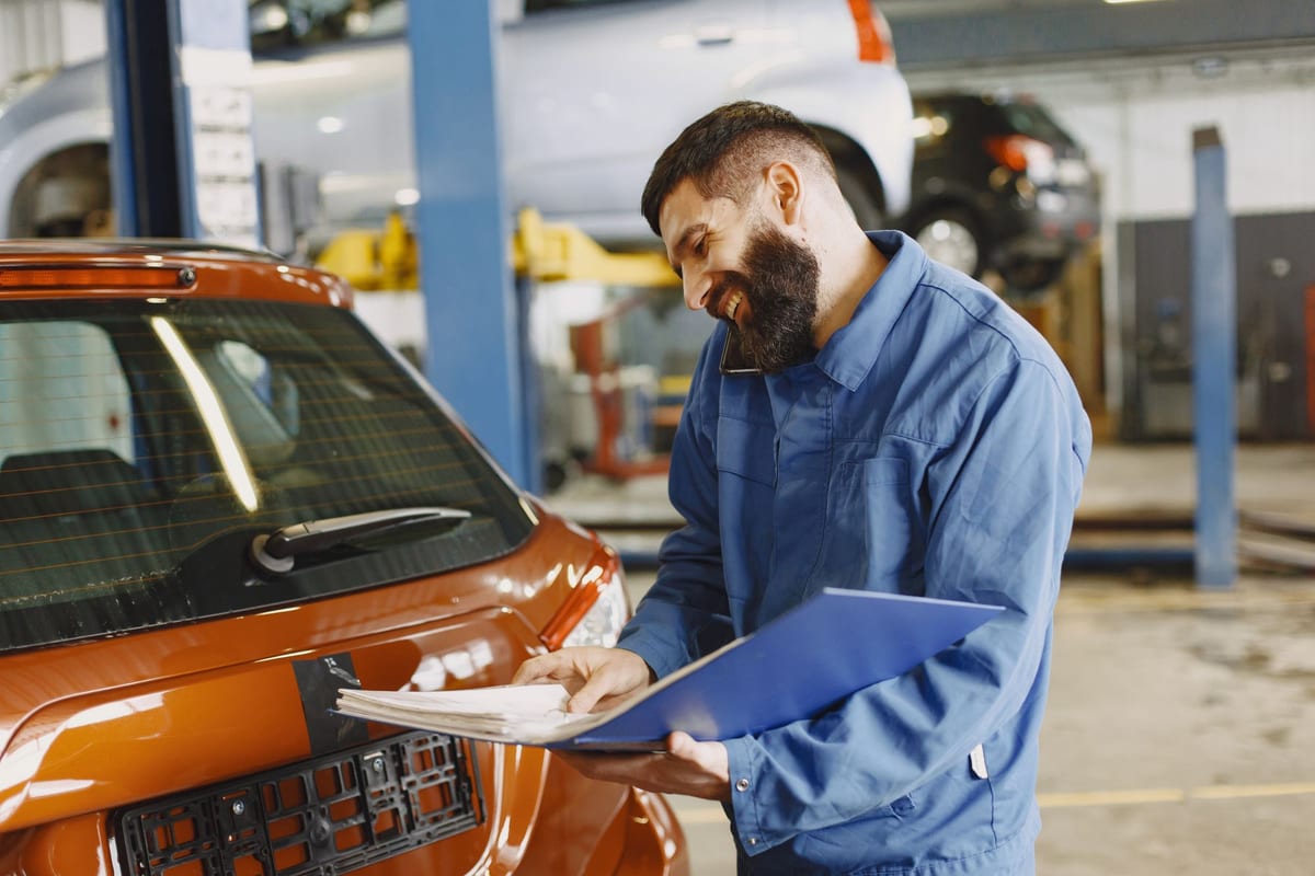 A person checking notes on a phone beside a car, comparing figures before heading into a shop.