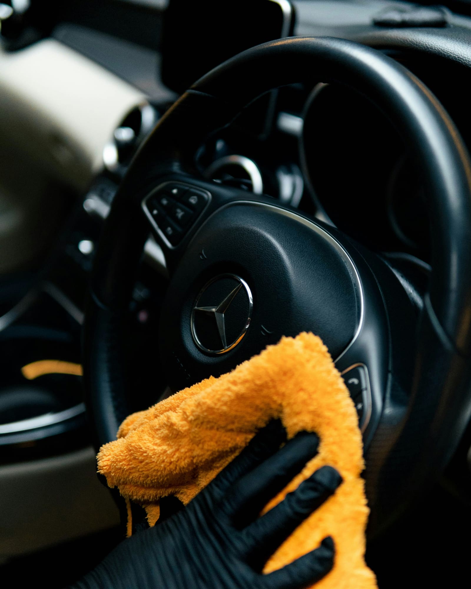 A person wiping down a car's finish with a yellow cloth after detailing work.