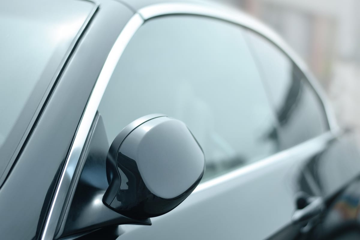 The side mirror and darkly tinted window of a clean, glossy car.